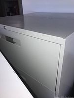Close-up of the front top and side of the cabinet showing the lock area and drawer handle.
