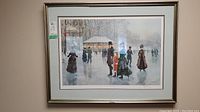 Framed limited edition print showing a vintage winter ice skating scene with several figures in period clothing skating and standing on the ice near a small pavilion.