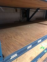 Photo showing plywood sheets stacked on metal shelving with visible wood grain and minor surface marks.