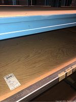 Plywood sheet on metal warehouse shelving with MaxSold lot tag visible