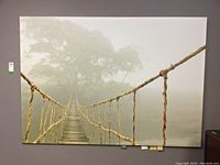 Full view of the large rope bridge print mounted on a wall showing the entire bridge fading into fog with trees in the background.