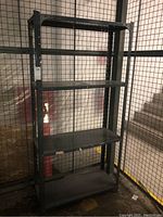 Front view of metal shelving unit showing four shelves and perforated vertical supports.