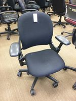 Front view of black Steelcase office chair showing padded cloth seat and back with vinyl armrests and adjustable height lever.