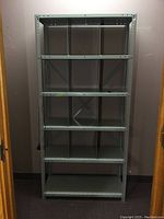 Front view of gray metal shelving unit with five shelves and vertical dividers on middle shelves