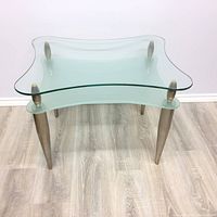 Two-tier Italian end table with sculptural clear glass tops and brushed chrome legs, showing oxidation on metal.