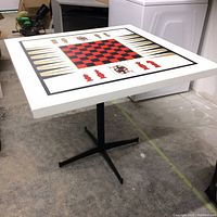 Angled view of the multi-game graphically printed tabletop and black metal base on concrete floor.