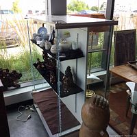Glass display case filled with some decorative items and tea set inside, showing glass shelves and LED lighting on sides.