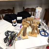 Overview of workshop lot contents including wooden mallets, melamine veneer, carbon monoxide detector, cables, fabric, templates, and small electronics.