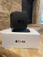 Apple TV 4K device shown atop the original white box labeled "Apple TV 4K".
