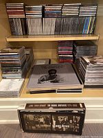 Shelf filled with a large quantity of CDs and box sets including Doobie Brothers Long Train Runnin box set and Eric Clapton Crossroads box set.