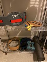 Photo of Speedo water weight belt on top shelf with Kadima paddle game and ball, metal wire shelving