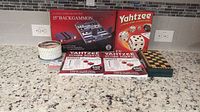 Countertop with all game items displayed: Yahtzee box, Backgammon box, wooden chess/checkers board, Yahtzee score pads, casino chips, dice, and playing cards