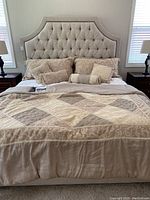 Front view of upholstered bed frame with tufted headboard, bedding and pillows