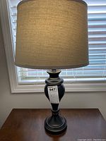 Full view of one matching black table lamp with grey fabric shade showing overall form and scale on wooden table.