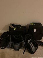 Photo of multiple black luggage and duffel bags arranged against wall, some with tags