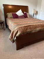 Left side angle showing wooden headboard and footboard, bedding with pillows