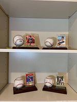 Four signed baseball and card sets displayed on a shelf
