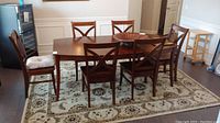 Full view of table and all six chairs on area rug, two chairs with cushions