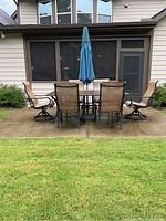 Overview of table, chairs, umbrella and stand on concrete pad