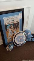 Framed UNC newspaper picture, wall clock, souvenir helmet and cap arranged on floor
