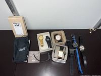 Photo of all seven watches displayed with some in original boxes and a Lizell pouch.