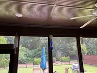 Wind chimes hanging on porch showing the blue glass bead chime in center with metal and wooden chimes on either side.