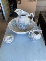 Five-piece antique pottery set with bowl, two pitchers, and two smaller bowls arranged on table showing design and size.