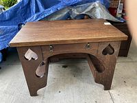 Front view of antique oak desk showing heart cutouts on side panels and drawer from front