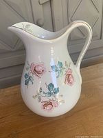 Front view of ceramic pitcher showing pink rose floral pattern and gold trim on handle and rim.