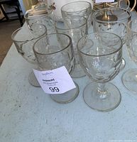 Eight clear glass antique water goblets arranged on a table, showing the honeycomb pattern and thick stems.