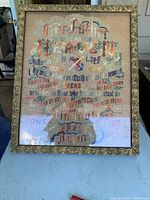 Full view of antique petit point embroidery displaying the Lord's Prayer in an ornate gold frame with original glass. The entire piece measures approximately 22 inches by 17 inches.