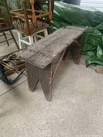 Side angle view of the rustic primitive pine farm bench showing thick plank seat, A-frame legs, and support braces.