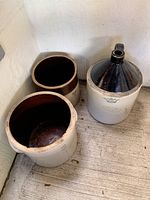 Overview of three antique stoneware pieces, two crocks and one jug, showing their size and condition.