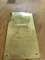 Photo of back of brass plaque showing solid brass surface with mounting holes