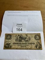 Full view of the three dollar banknote on plain background with auction label and lot number