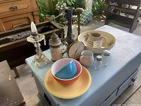 Tabletop showing two nesting pastel Pyrex dishes, ceramic beer stein with pewter lid, glass lamp, small clock, ceramic creamer, and salt and pepper shakers.