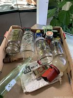 Photo showing various glass jars including canning jars (Gem, Perfect Seal) and a Trader bottle, along with a red nutmeg grinder and other collectible jars.