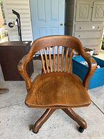 Front view of vintage Krug solid oak office chair showing curved arms, spindle backrest, and contoured wooden seat.