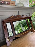 Angled side view highlighting the wood detailing, brass hook placement, and mirror condition.