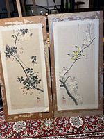 Two paintings on backing boards showing birds and flowering branches with water damage and torn edges