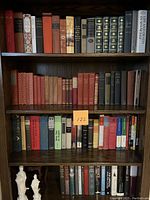 Full view of four shelves populated with hardcover books in various bindings.