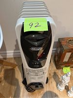Front view of Delonghi electric oil heater showing the brand logo, control dial, switches, and power cord.