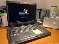 Photo of Fujitsu Lifebook laptop powered on, displaying Windows XP boot screen.