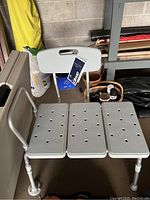 Front view of the aluminum transfer tub bench showing perforated seat and backrest with handle cutout