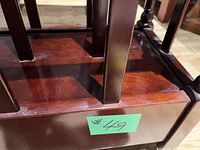 Close-up of the bottom platform and vertical slats of the wood magazine stand with dark finish, showing the construction and finish of the wood, and a lot number sticker.