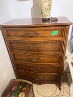 Full view of the wood storage cabinet showing four drawers with ornate metal handles and curved drawer fronts.