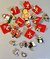 Collection of vintage Avon brooches and pins with Christmas and animal themes, displayed on red mount cards and laid out on a surface.