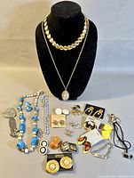 Wide view of entire lot showing necklaces on display bust and multiple earrings and beaded necklaces laid out on table.