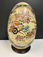 Front view showing floral cart wheel design on cream background on the egg-shaped ceramic.