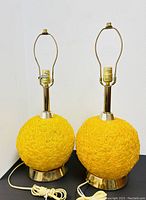 Pair of yellow spun Lucite Mid-Century Modern table lamps with brass fittings shown side by side.